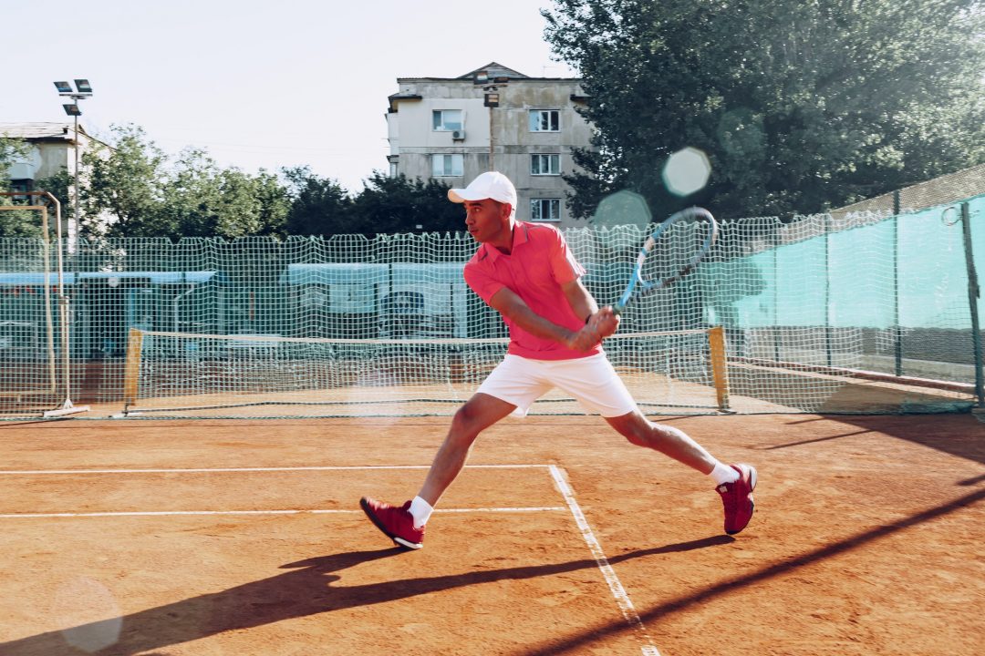 middle aged man playing tennis on outdoor tennis filed